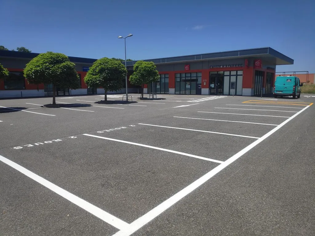 Vue générale d’un parking professionnel avec places, flèche et passage piéton blancs