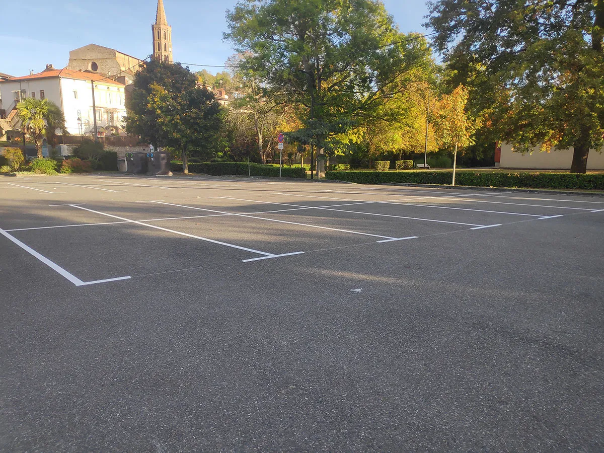 Parking extérieur avec plusieurs rangées de places tracées en blanc