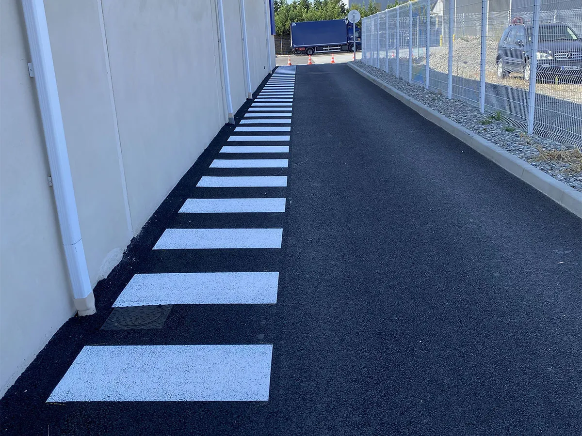 Passage piéton blanc tracé le long d’un bâtiment professionnel
