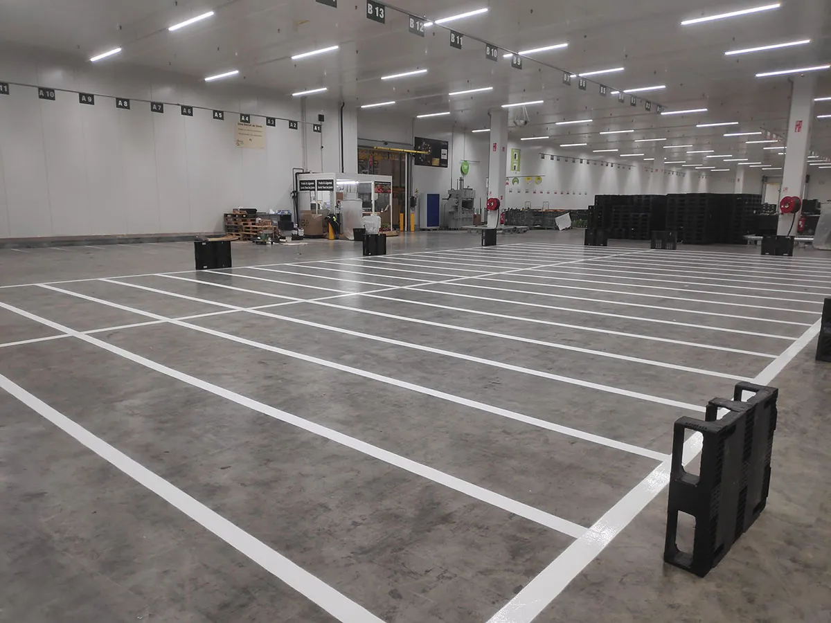 Plateforme logistique intérieure avec de nombreuses zones rectangulaires tracées en blanc