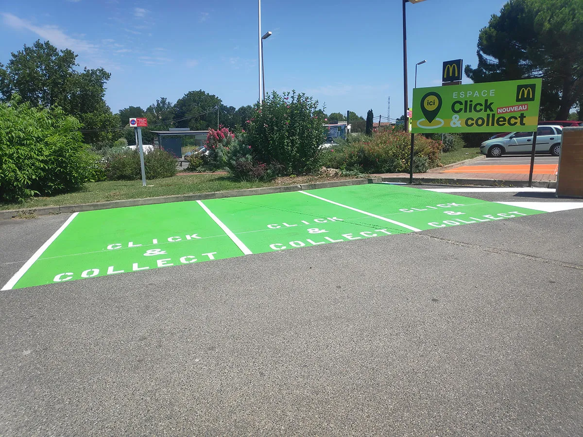 Trois places vertes Click & Collect avec inscriptions blanches et grand panneau directionnel